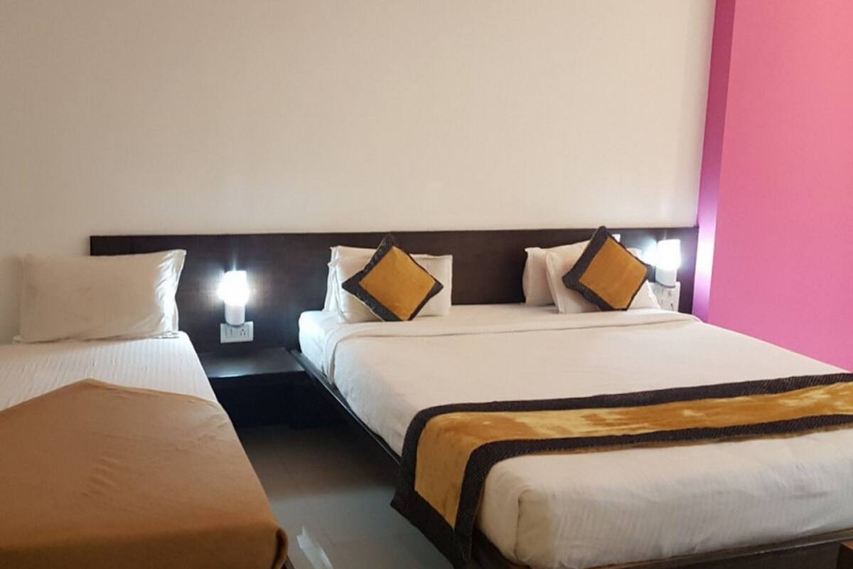 Habitación de hotel con dos camas, cada una con ropa de cama blanca y cojines decorativos.