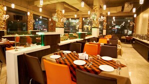Un restaurante con varias mesas, sillas y una barra con vitrina.