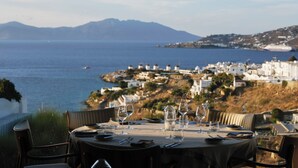 Mesa lista para comer con vista al mar y a un pueblo costero.