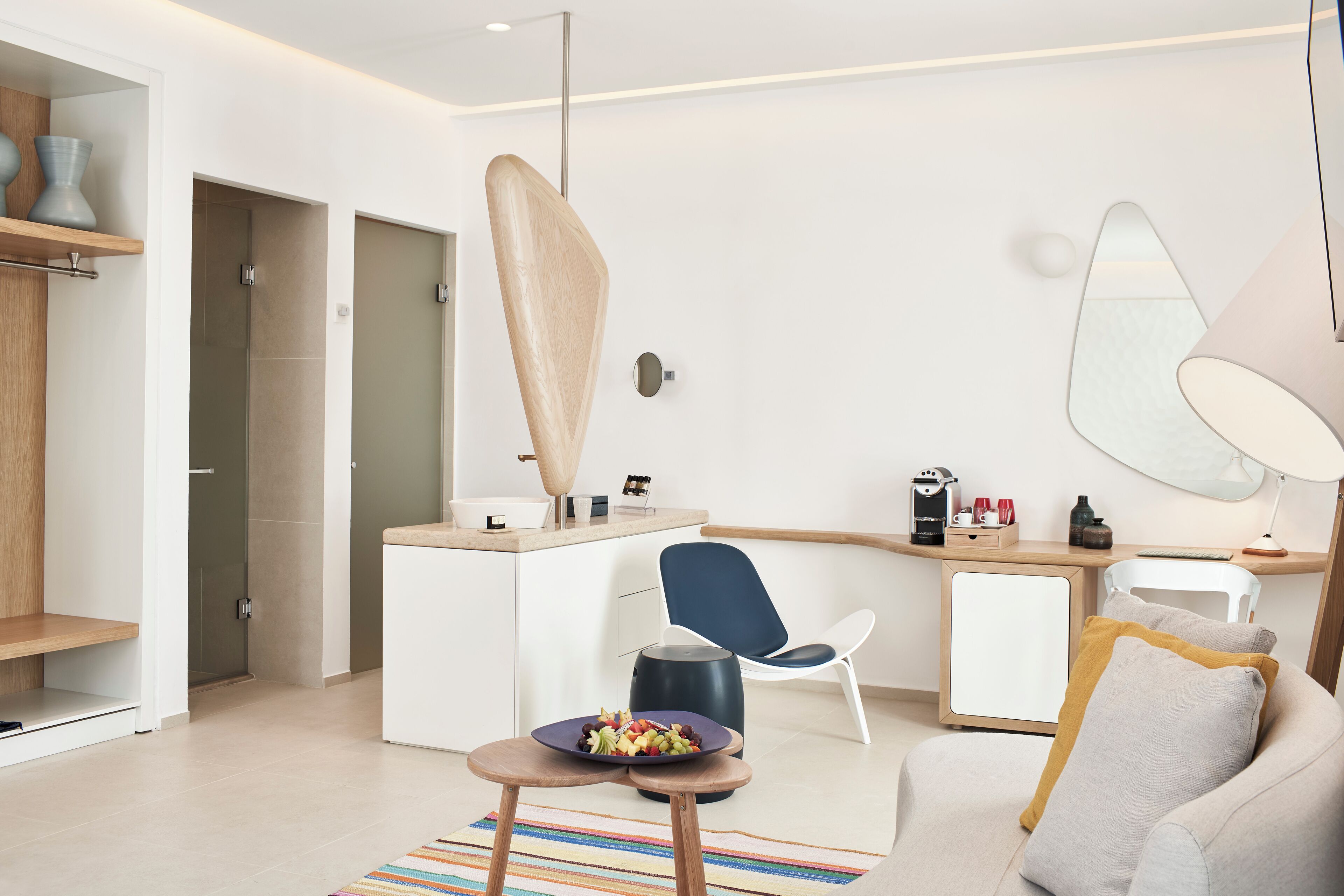 Ein modernes Hotelzimmer mit Küchenzeile, Essbereich und einer Sitzecke mit Sofa und Sesseln.