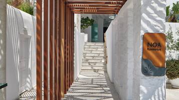 A covered walkway leading to a building with a sign for NOA Restaurant.