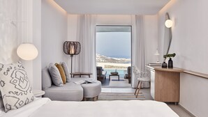 Una habitación de hotel moderna con una cama grande, un sofá, un escritorio y vistas al mar.