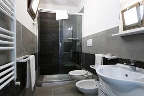 A modern bathroom with a glass-enclosed shower, two toilets, and a white sink. - Maresidence (Salve)