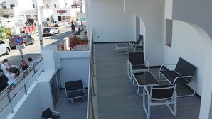 Ein Balkon mit weißen Geländern, schwarzen Lounge-Stühlen und Blick auf die Straße darunter.