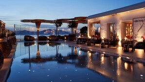 Un espace piscine paisible offrant une vue dégagée sur les montagnes, un mobilier d’extérieur moderne et un bâtiment bien éclairé.