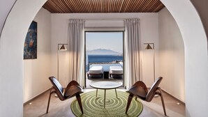 Ein Zimmer mit Meerblick, ein runder Tisch, zwei Stühle und eine Decke mit Holzbalken.