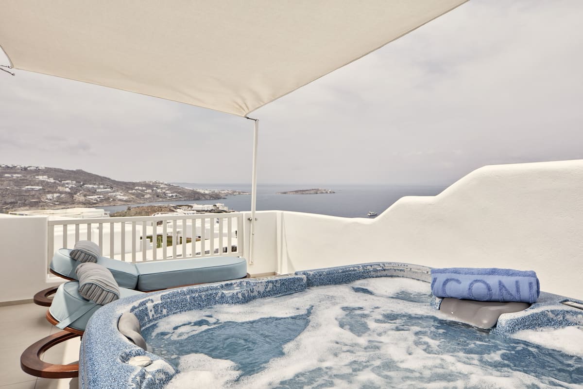 Un jacuzzi avec vue sur la mer, un balcon blanc et une serviette bleue.