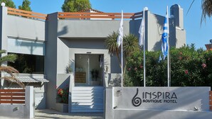 A modern boutique hotel with a prominent entrance, a flag, and a signboard.