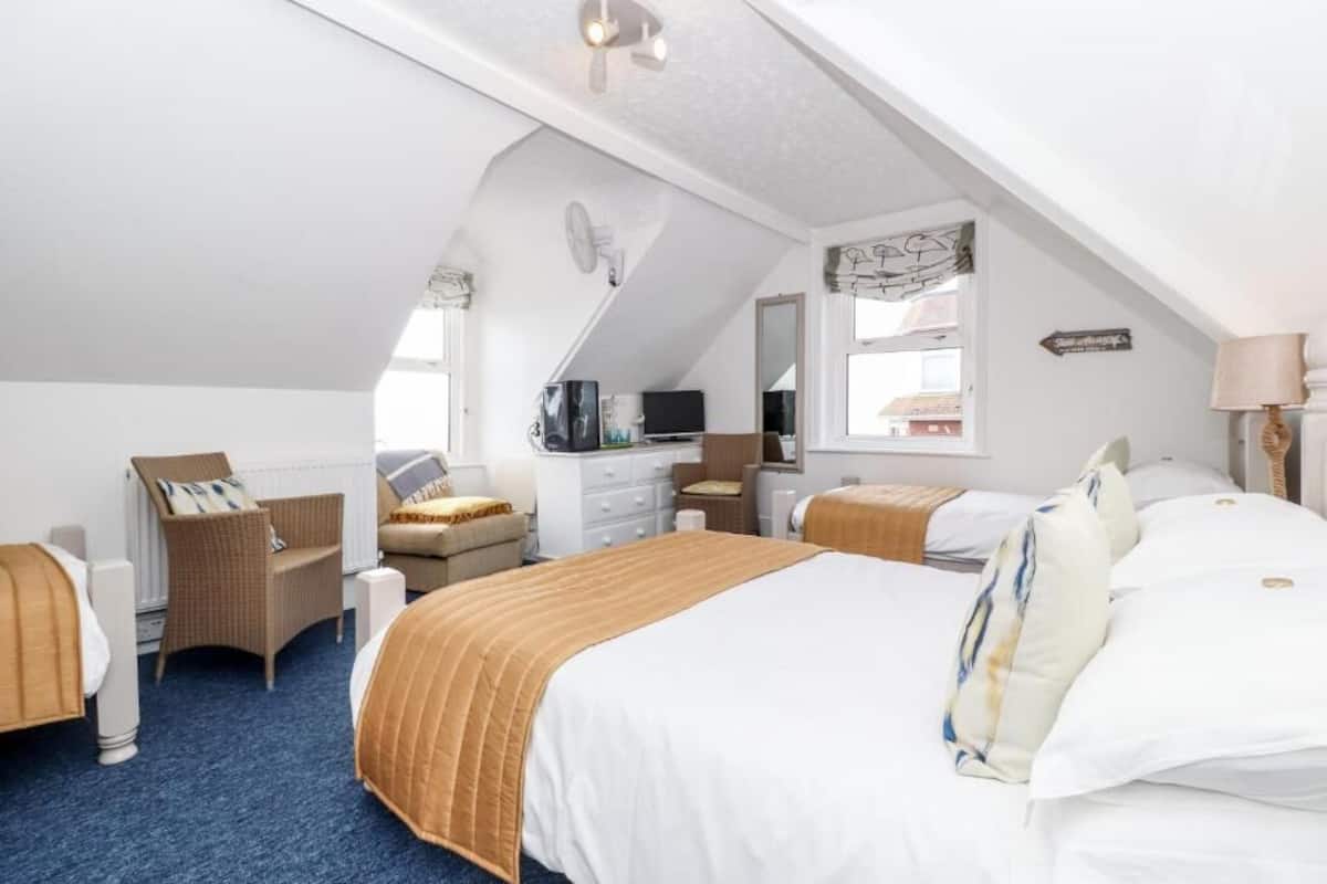 A bedroom with a large bed, two bedside tables, a dresser, a chair, and a television.