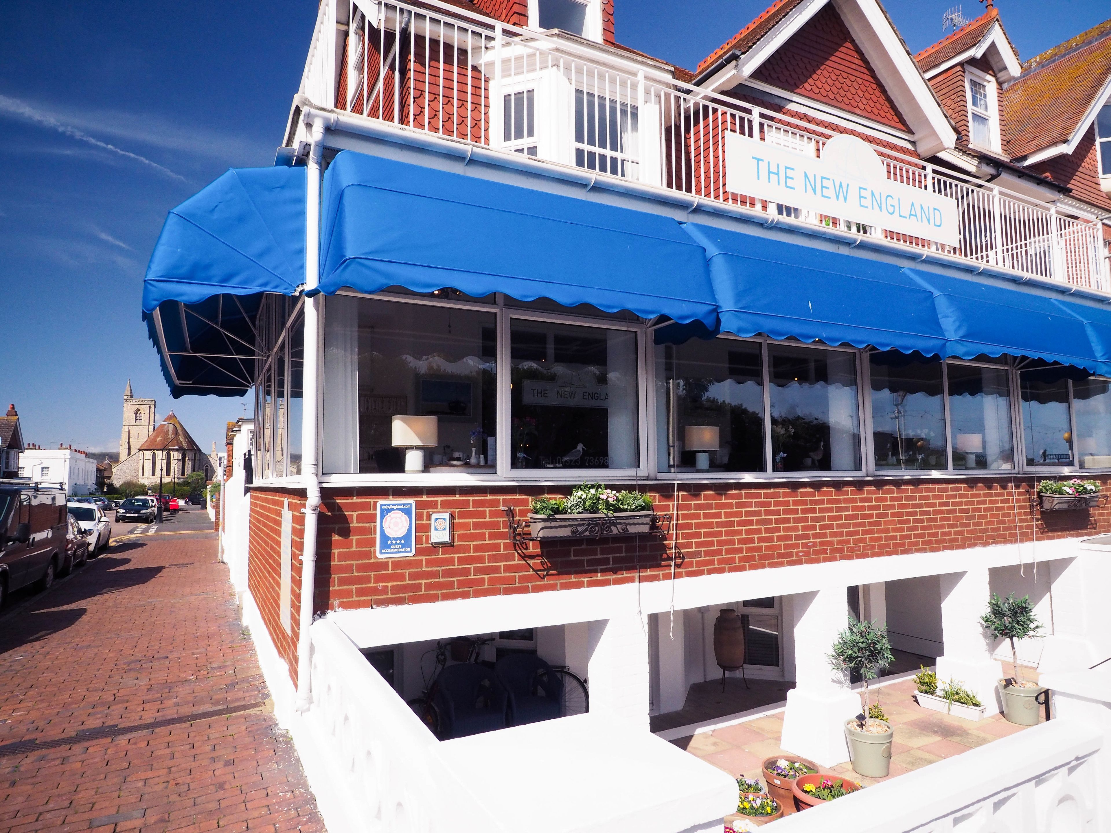 A building with a blue awning and the sign "The New England".