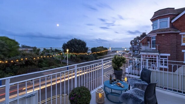 A balcony with a view of a road, a street lamp, and a small table with chairs. - The New England (Eastbourne)