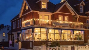 A traditional brick building with a balcony and large windows, labeled "The New England." - The New England (Eastbourne)