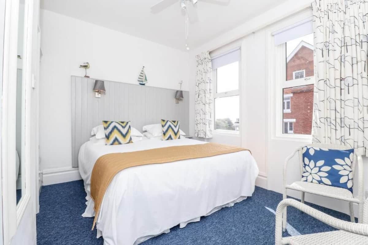 A bedroom with a bed, a chair, a window, and a ceiling fan.