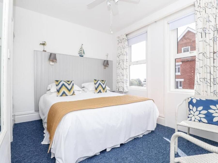 A bedroom with a bed, a chair, a window, and a ceiling fan.