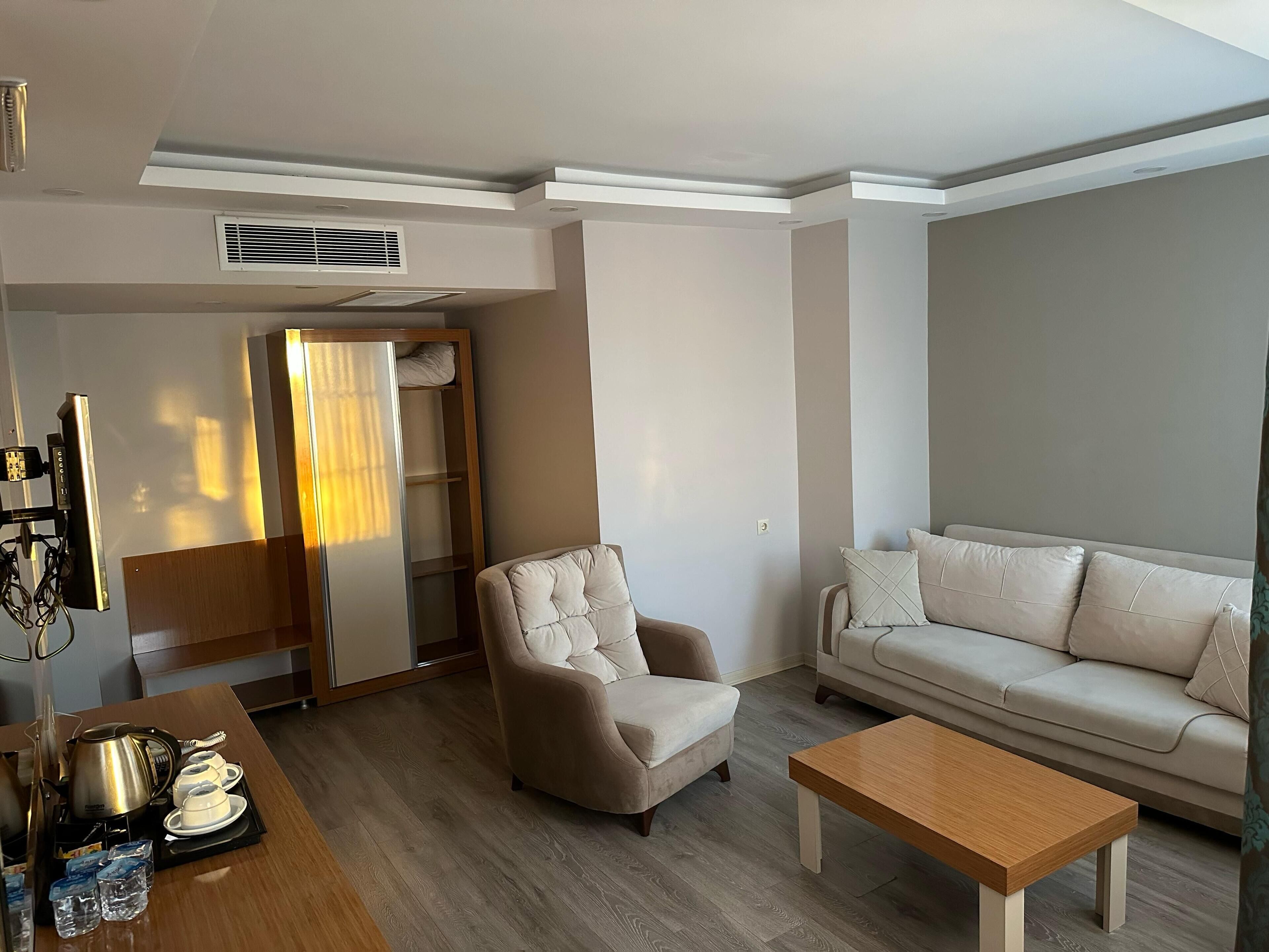 Una sala de estar moderna con sofá, sillón, mesa de centro y comedor con mesa y hervidor.