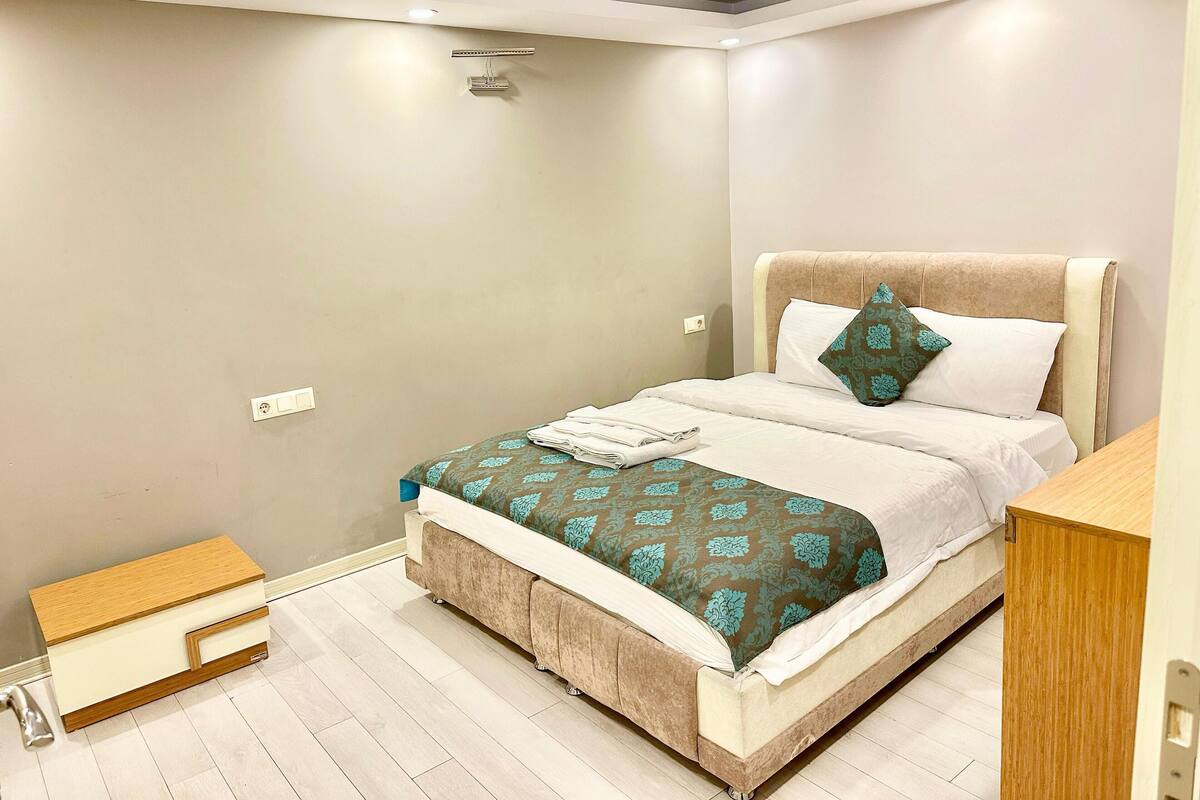 A neatly arranged bedroom with a bed, bedside table, and a small wooden cabinet.