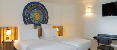 Une chambre d’hôtel avec un grand lit, deux tables de chevet avec des lampes, un téléviseur à écran plat et un bureau avec une chaise.
