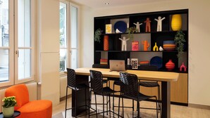 A modern kitchen with a wooden table, black chairs, and a black shelving unit with various decorative items. - Korner Sorbonne (Paris)