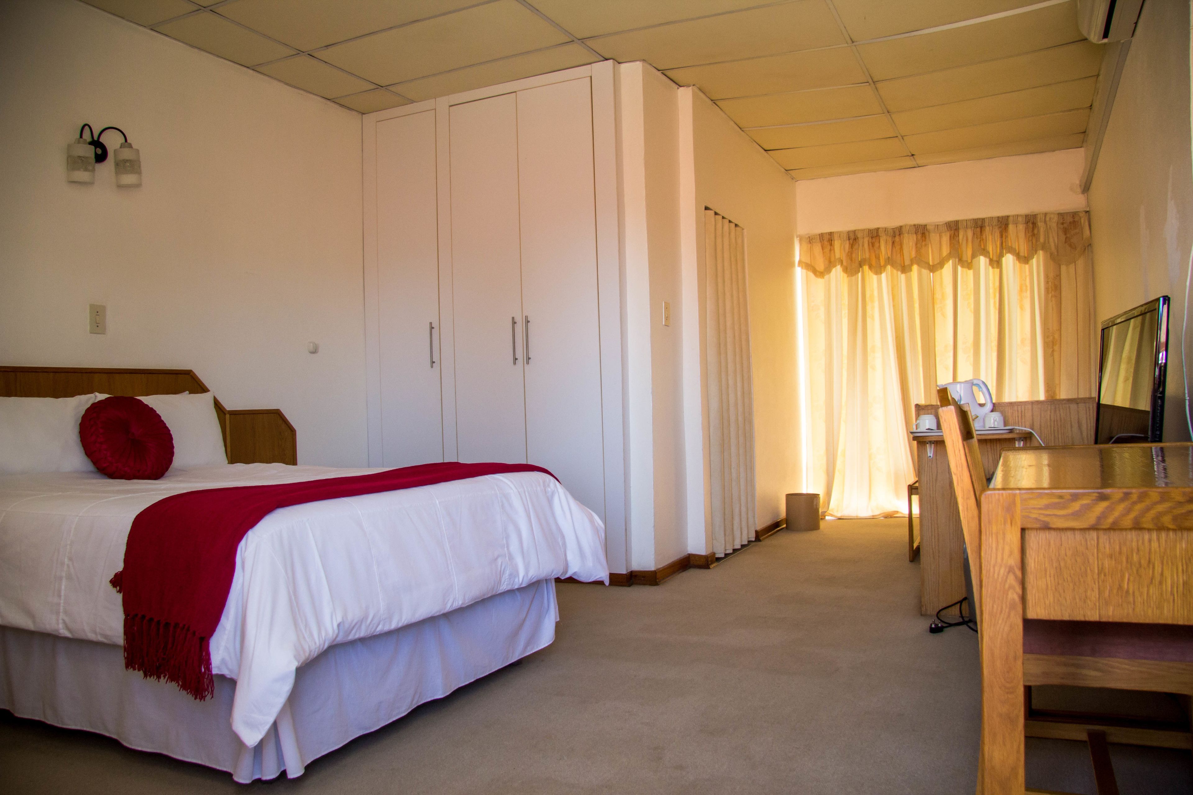 Una habitación de hotel con una cama, un escritorio y un armario.