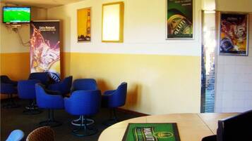 A seating area with blue chairs, a television on the wall, and posters on the walls.