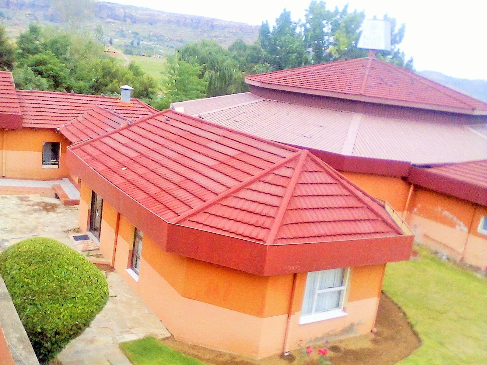 Un bâtiment doté d’un toit rouge, d’un petit jardin et offrant une vue sur le paysage environnant.