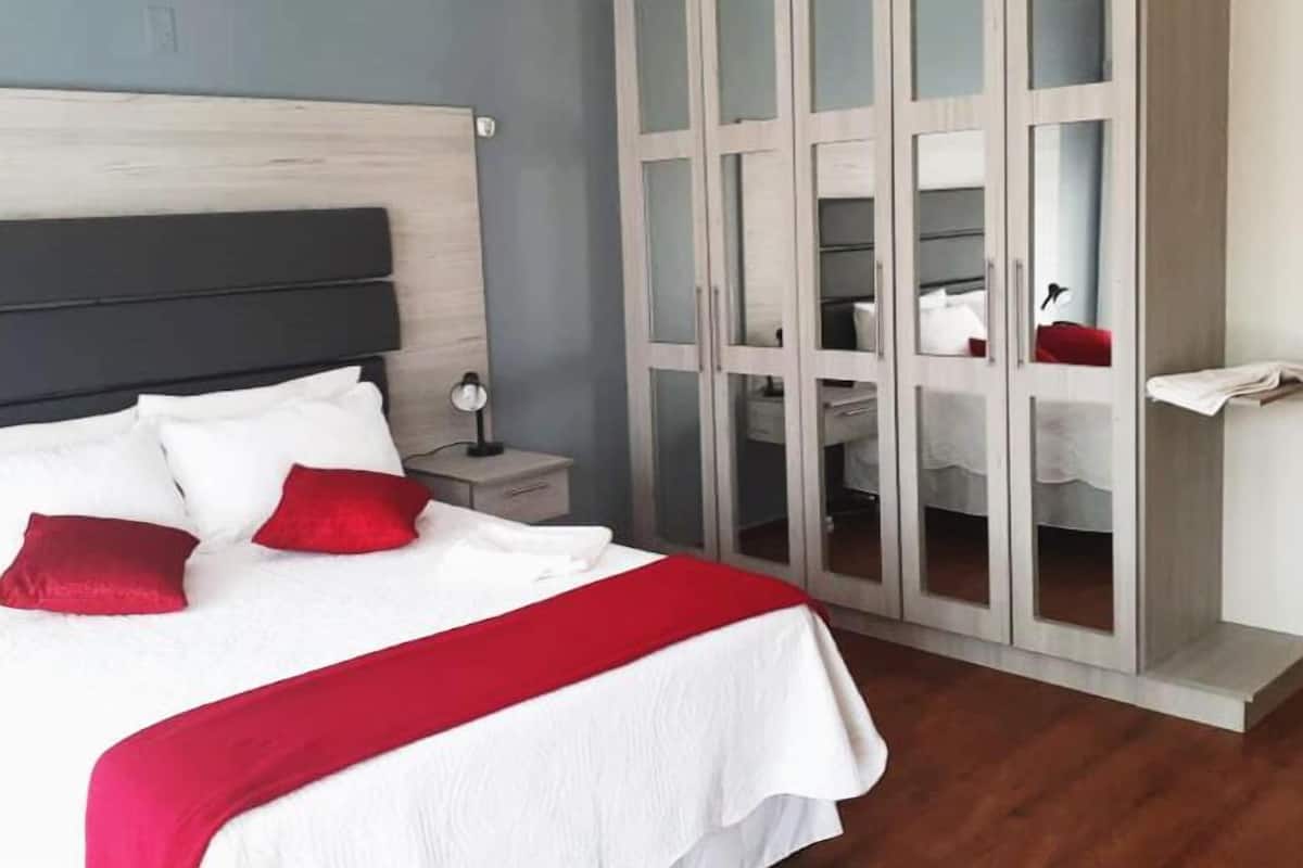 Une chambre à coucher comprenant un lit, une table de chevet et une armoire aux portes miroir.