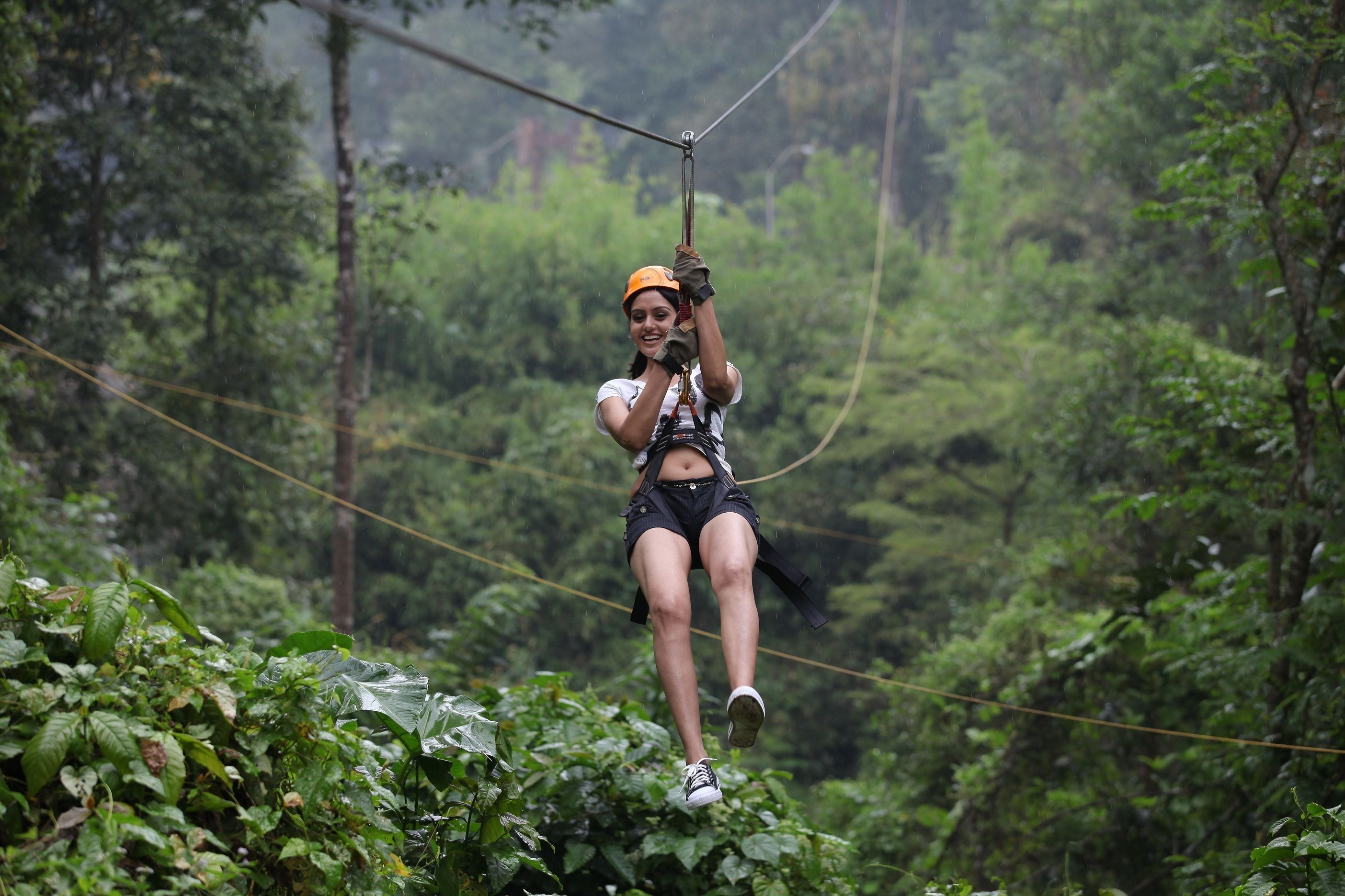 Iemand beleeft een zipline-avontuur door een weelderig, groen bos.