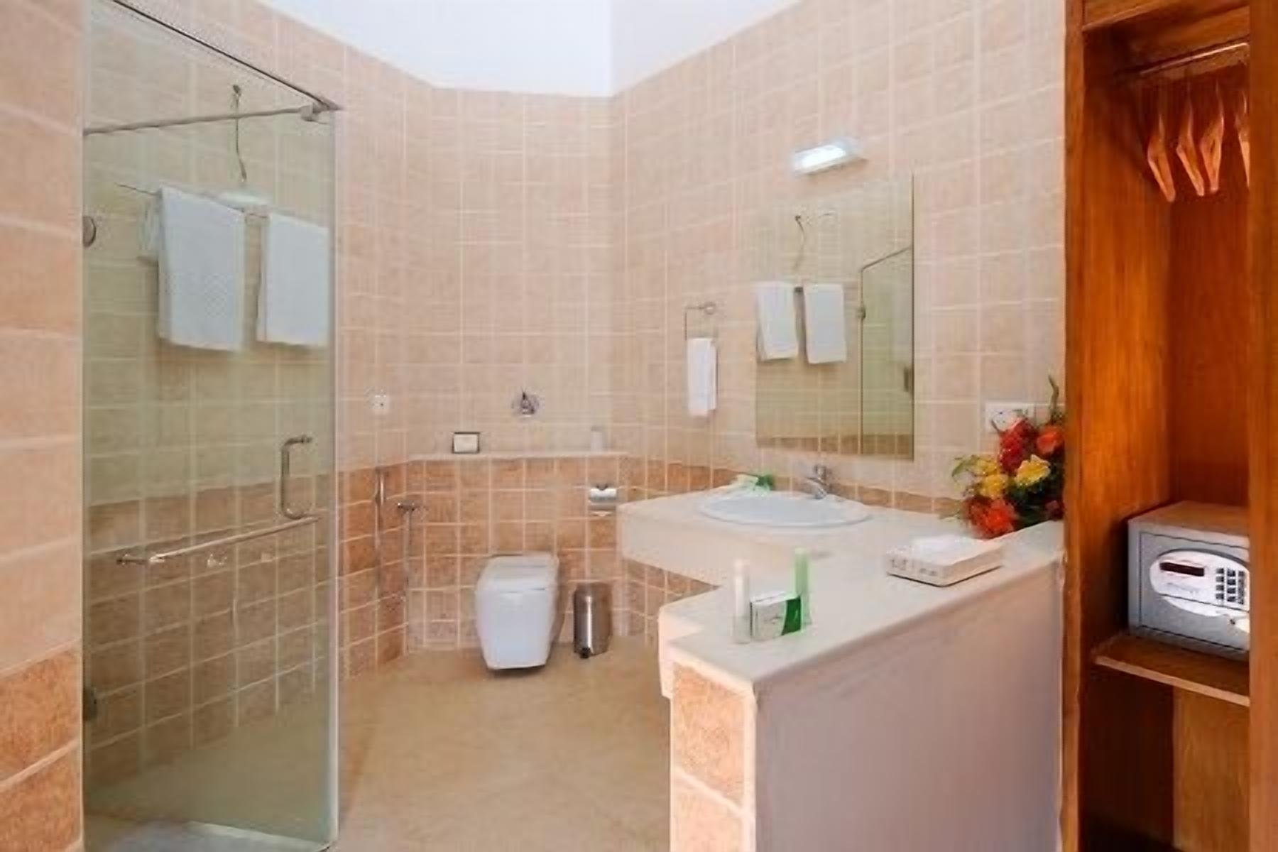 A modern bathroom with a glass shower enclosure, a sink with a mirror, and a small wooden cabinet.