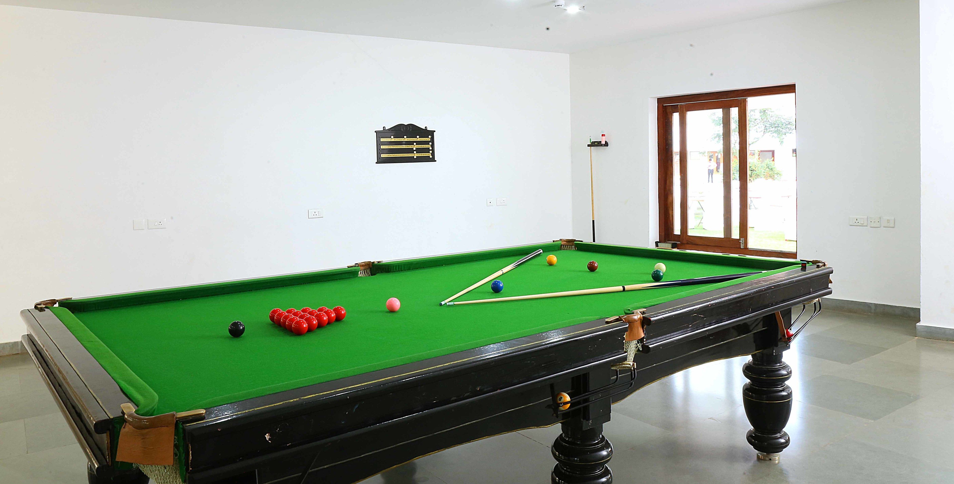 A pool table with balls and cues, a window with a view, and a plaque on the wall.