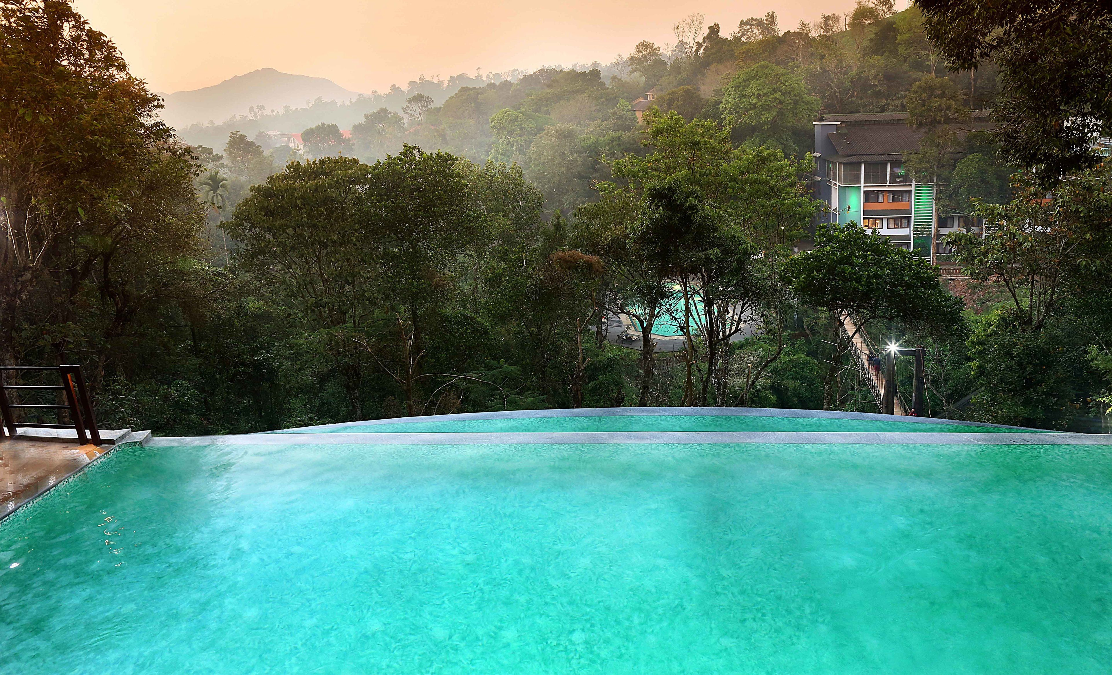 Una vista despejada de una piscina rodeada de exuberante vegetación y una montaña al fondo.