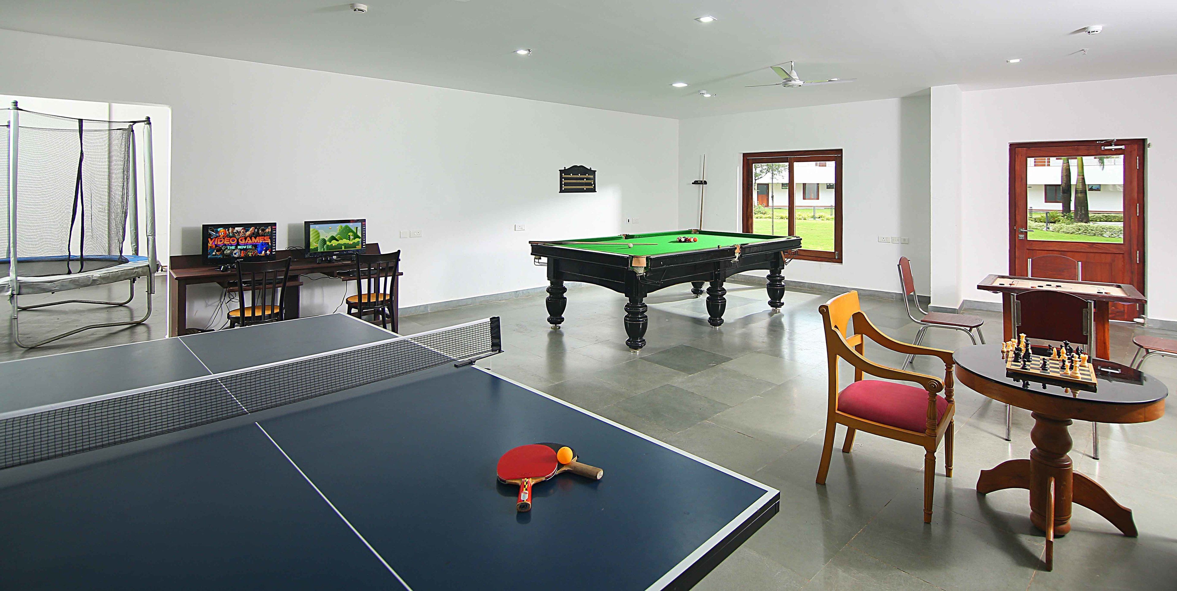 Een kamer met een tafeltennistafel, een pooltafel en een tafelvoetbaltafel.