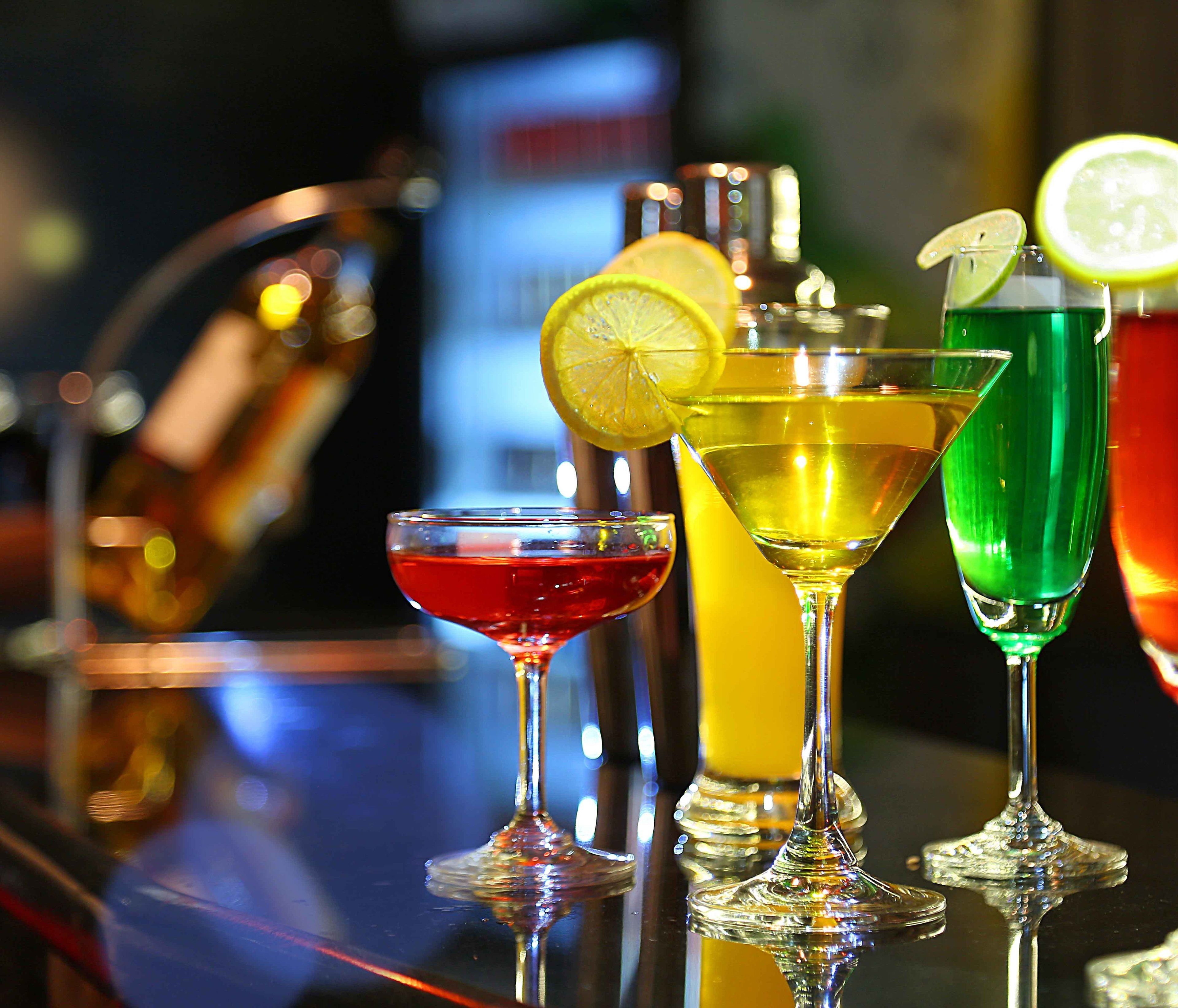 Une variété de cocktails colorés sont présentés sur le comptoir d’un bar.