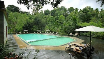 Relax by the serene pool surrounded by lush greenery and comfortable lounge chairs.