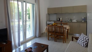 A modern apartment with a dining area, kitchen, and a balcony with curtains. - Pavloudis Apartments (Polygyros)