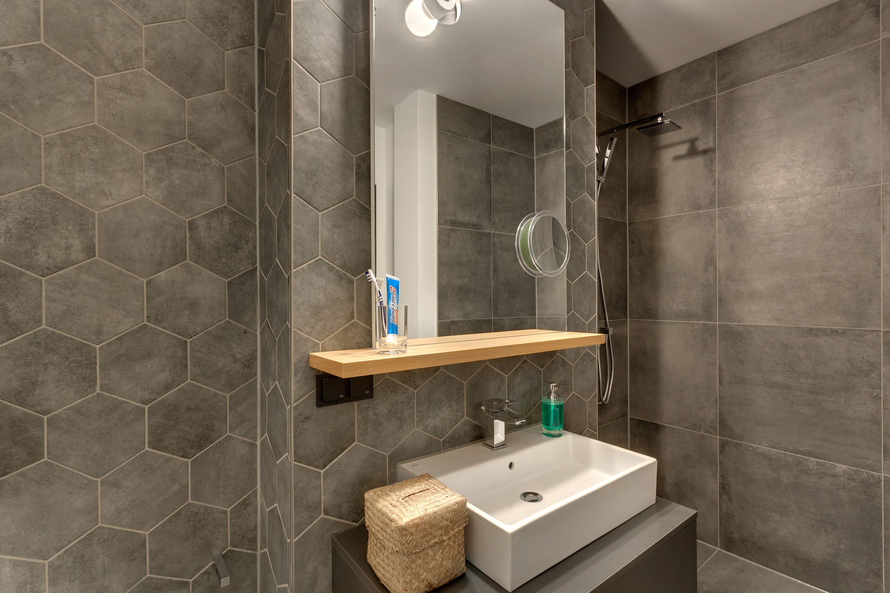 A modern bathroom with a rectangular sink, a mirror above it, and a showerhead.