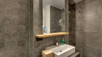 A modern bathroom with a rectangular sink, a mirror above it, and a showerhead.
