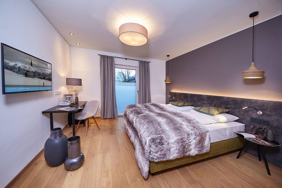 Een moderne slaapkamer met een groot bed, een bureau en een stoel.