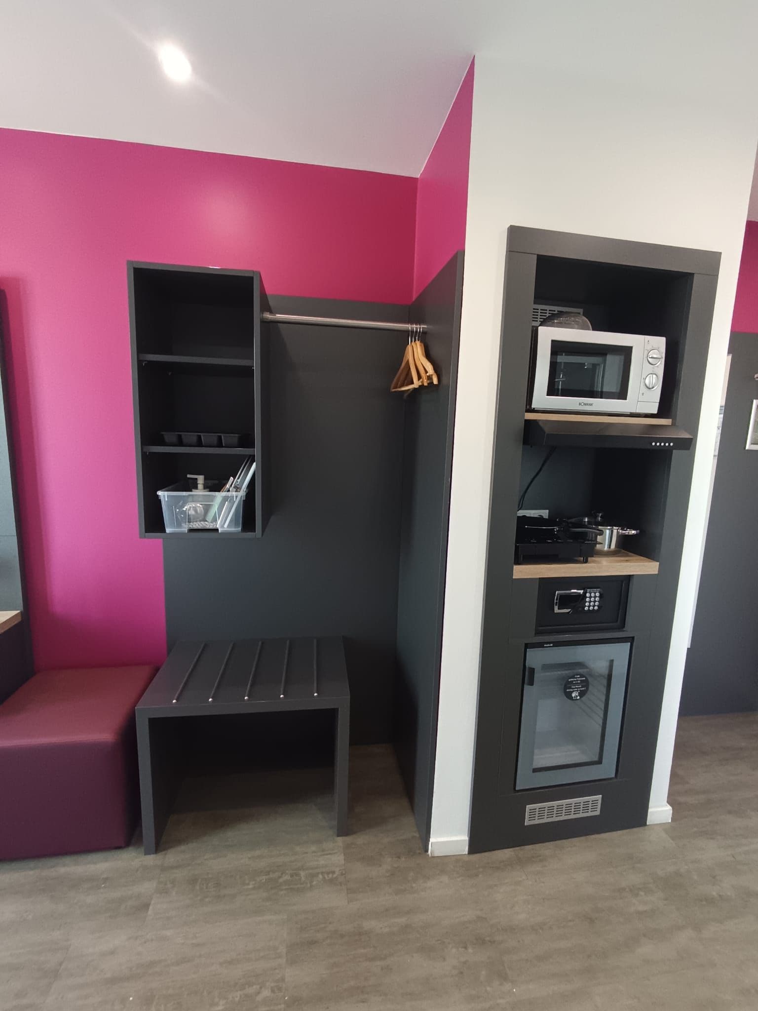 A compact kitchenette with a microwave, stove, and storage shelves.