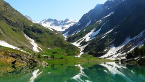 Paisagem de montanha com um lago límpido refletindo os picos ao redor.