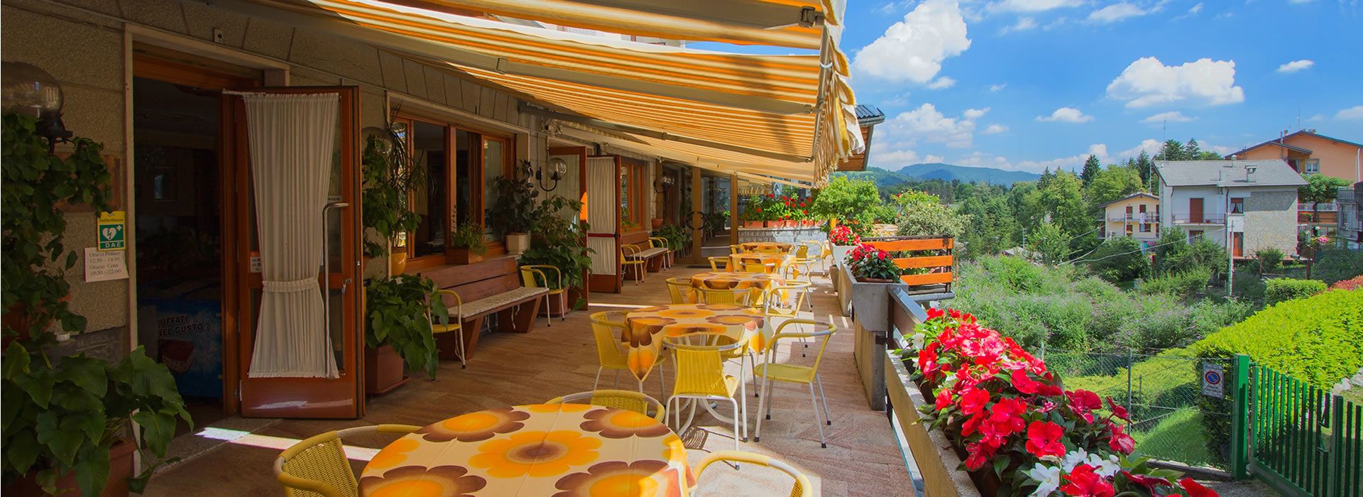 Une terrasse avec des sièges extérieurs, des plantes en pot et une vue sur la verdure et les bâtiments environnants.