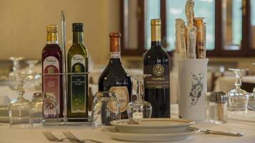 Une table dressée pour le dîner, avec différentes bouteilles de vin, des verres et des couverts.