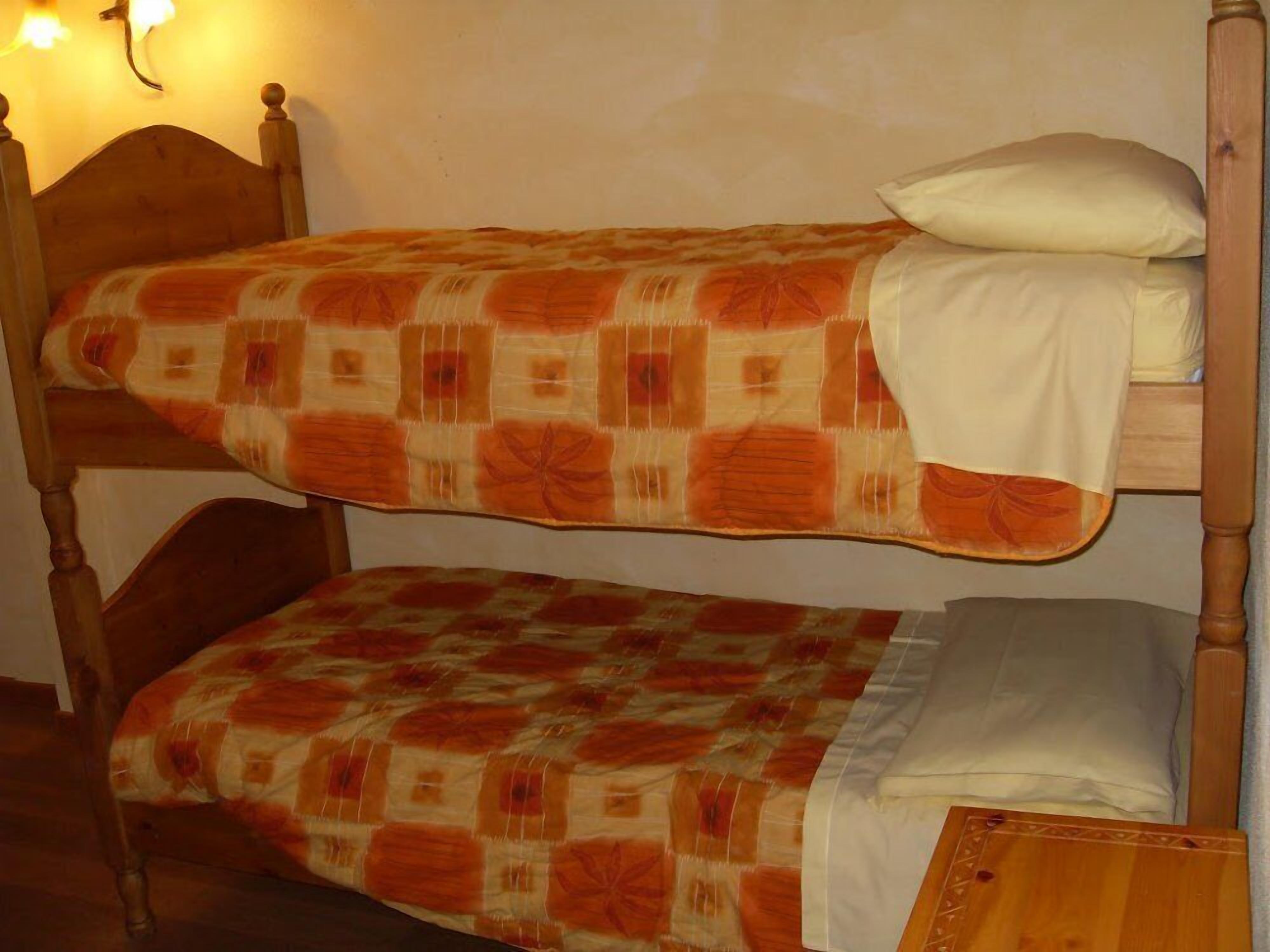 A bunk bed with a patterned bedspread and a pillow on top.