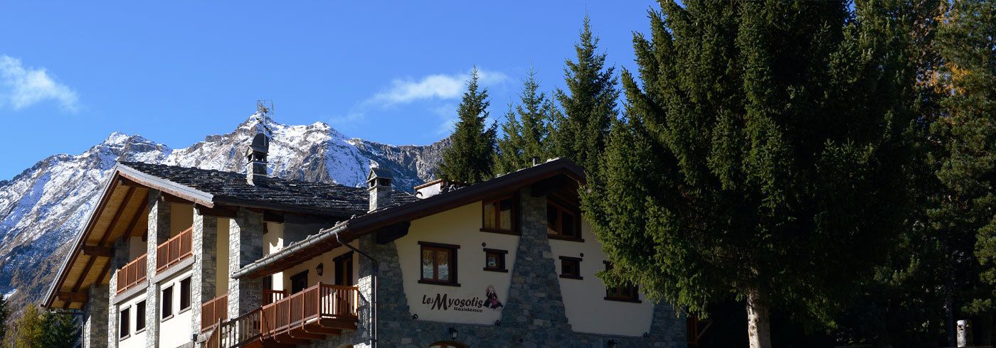 Eine Berghütte aus Stein und Holz mit einem Balkon und einem Schild, auf dem 'Le Myosotis' steht.