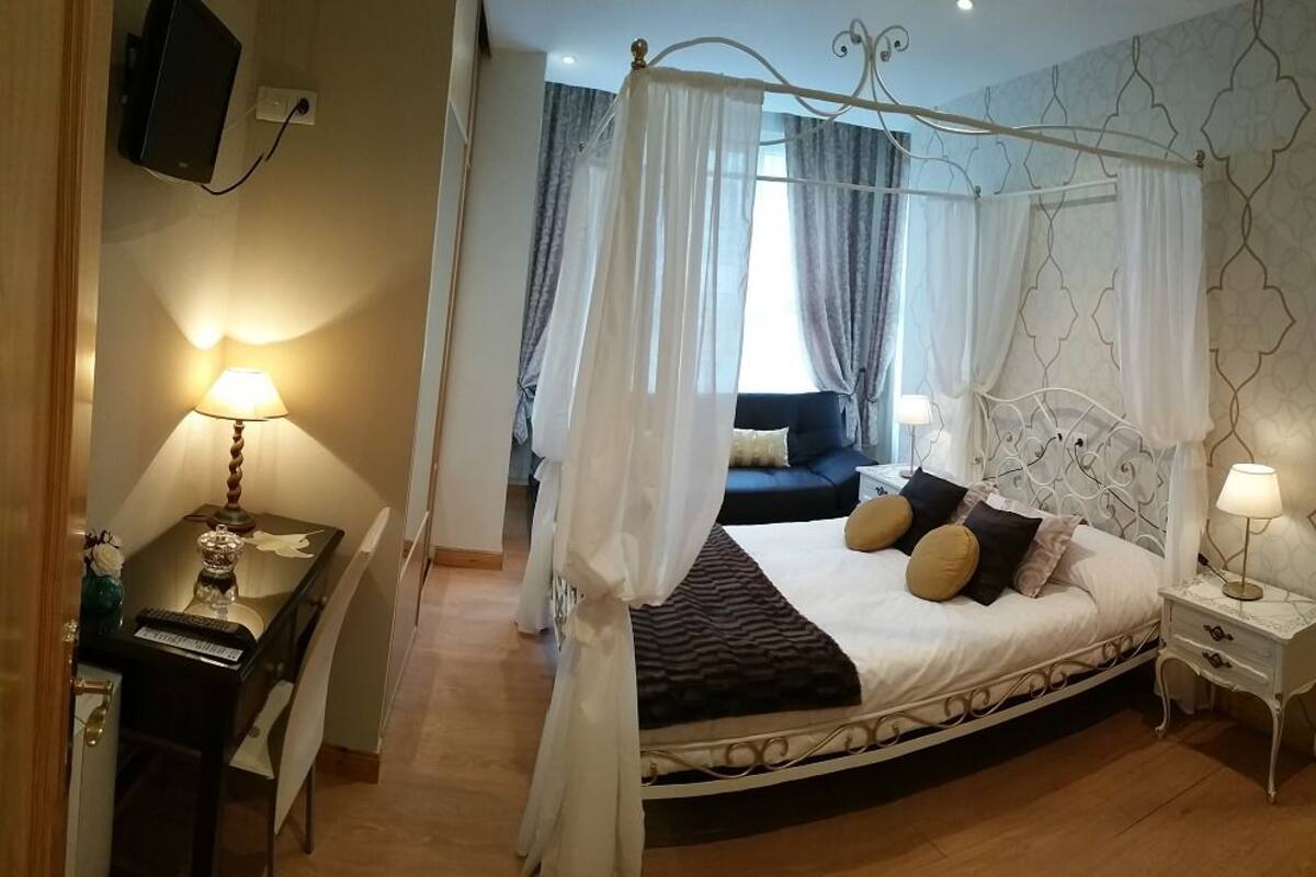 Une chambre à coucher avec un lit à baldaquin, un bureau avec une lampe et une table de chevet avec une lampe.