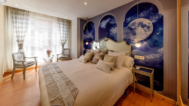 Ruime slaapkamer met een groot bed, twee stoelen, een klein tafeltje en een nachtkastje.