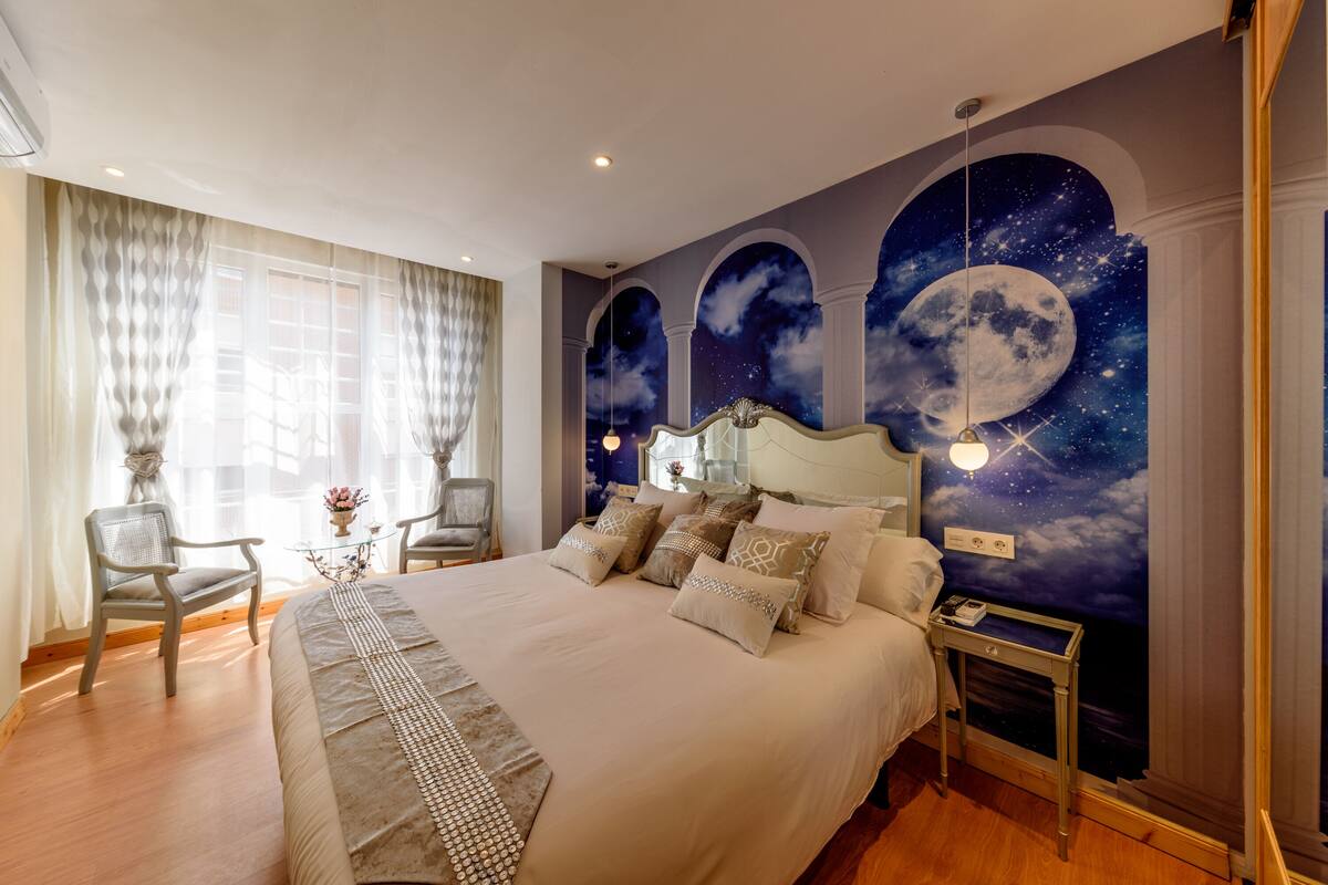 Une chambre spacieuse avec un grand lit, deux fauteuils, une petite table et une table de chevet.