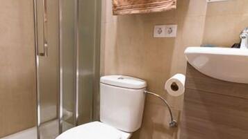 Une salle de bain avec une douche à parois de verre, des toilettes et un lavabo surmonté d’un porte-serviettes.