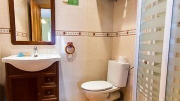 Un baño con piso de mármol, lavamanos, inodoro y zona de ducha.