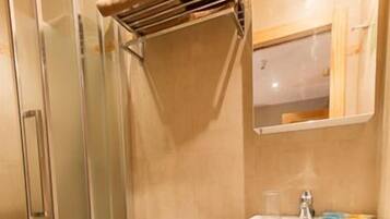 A bathroom with a glass shower enclosure, a toilet, and a sink with a mirror above it.