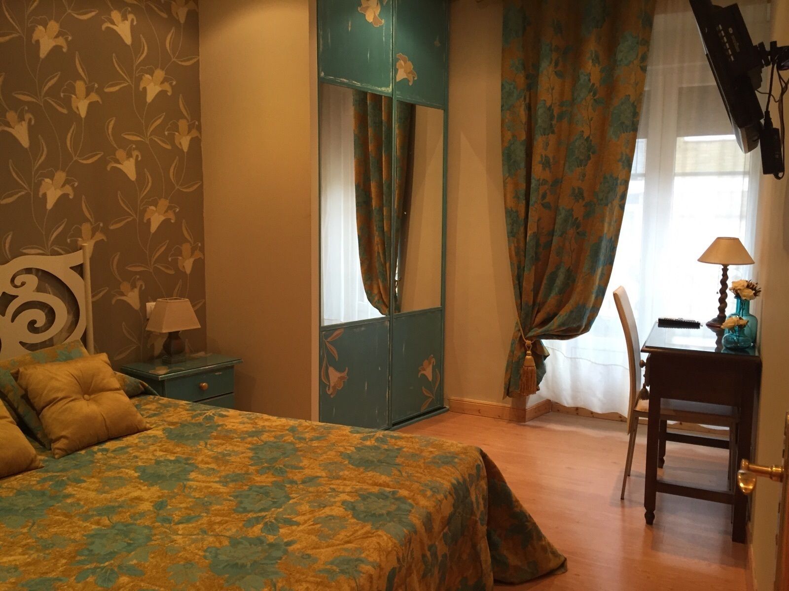 A bedroom with a bed, a dresser, a desk with a lamp, and a chair.